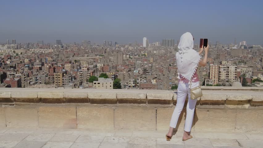 Young adult girl takes pictures of Egypt city. European woman.