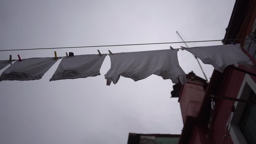 Clothes on clothesline outside. laundry drying outdoor at old italian street. Typical tourist place in Venetian lagoon Italy. Beautiful water canals and colorful architecture Burano Italy | Shutterstock HD Video #1106936247