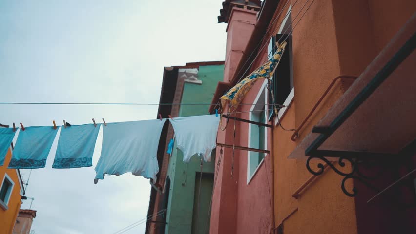 Clothes on clothesline outside. laundry drying outdoor at old italian street. Typical tourist place in Venetian lagoon Italy. Beautiful water canals and colorful architecture Burano Italy | Shutterstock HD Video #1106936253