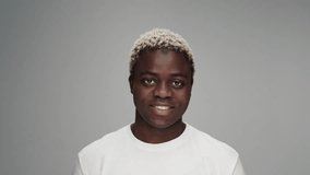 Portrait of Young Black Man Looking at Camera in Color Studio Shot. Adult Afro Boy Isolated Alone on Grey Background Close-up. Headshot of 20s African American Person Turning Head and Smiling Happy 4k - Powered by Shutterstock - Get 15% off with code: PIKWIZARD15