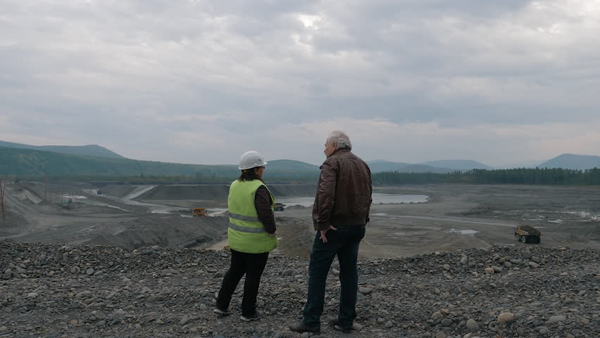 Two workers discussing the process of gold ore mining at the quarry. Workers overseeing the heavy mining machinery collecting gold. Workers monitoring the gold extraction at the open-pit mine. Royalty-Free Stock Footage #1106936967
