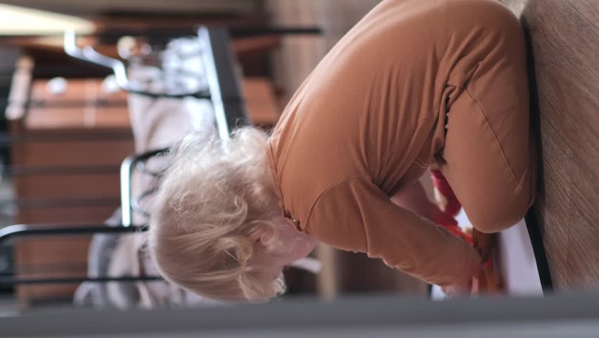 A 2-year-old child sits on the floor in the room and plays, turns his head and smiles sweetly.