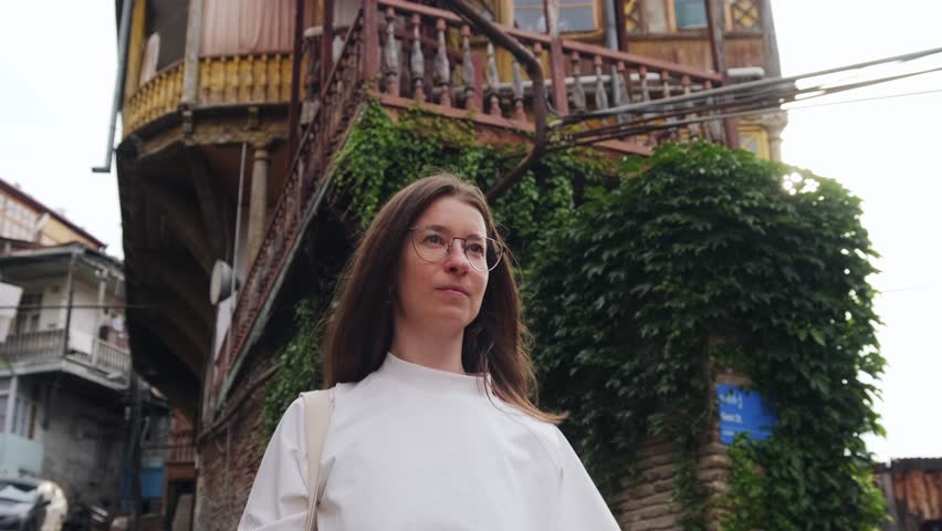 A young woman walks through the old streets of Tbilisi. Old city, authentic architecture of Georgia.