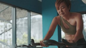 Training and cardio exercise of Asian woman as bodies move in sync with the rhythm of the bike. Witness the determination and motivation that fuel each pedal stroke, creating wellness and vitality. - Powered by Shutterstock - Get 15% off with code: PIKWIZARD15
