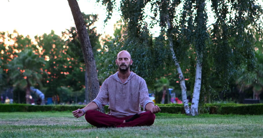 In the park, an middle-aged man sits in a meditative posture, finding tranquility and inner calm through his practice Royalty-Free Stock Footage #1106948001