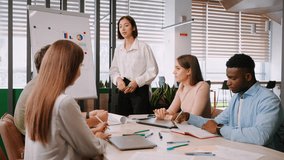 Asian woman office worker gives report to colleagues showing diagrams. Coworkers clap hands and smile congratulating on successful completion of project slow motion - Powered by Shutterstock - Get 15% off with code: PIKWIZARD15