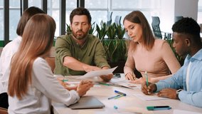 Pensive office workers discuss documents working together at meeting sitting at table. Entrepreneurs create action plan for new business project slow motion - Powered by Shutterstock - Get 15% off with code: PIKWIZARD15
