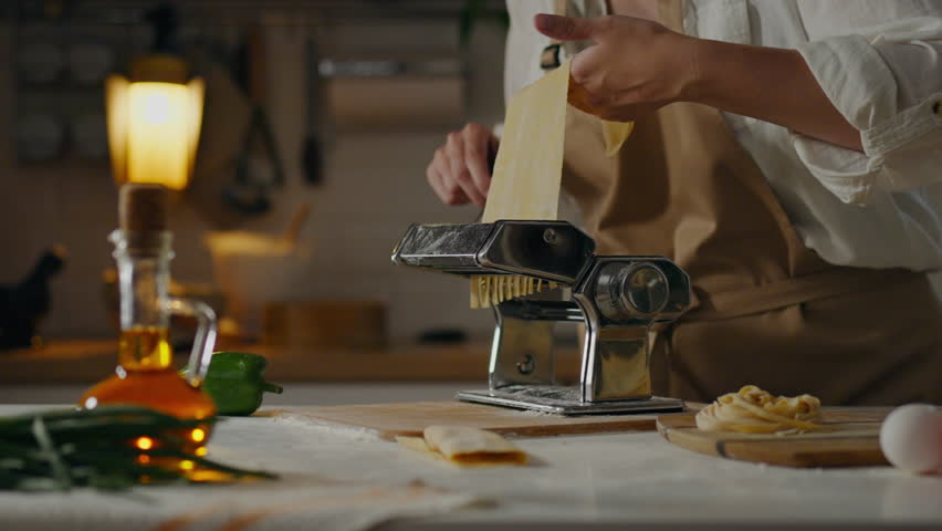Dough, home kitchen mistress concentrated Manual machine rolls the dough into a thin sheet In an authentic pasta workshop. male baker molding pasta applies new pasta cooking methods, homemade pasta Royalty-Free Stock Footage #1106950135