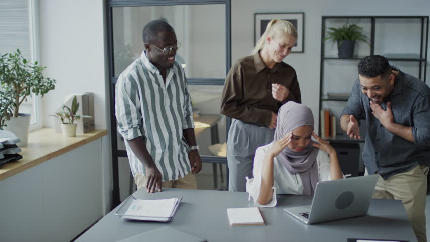 Group of three multi-ethnic colleagues making mock of their Muslim colleague at work in office Royalty-Free Stock Footage #1106951981