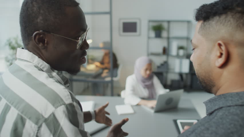 Selective focus shot of African American and Middle Eastern men standing in office defaming their female colleague Royalty-Free Stock Footage #1106953365