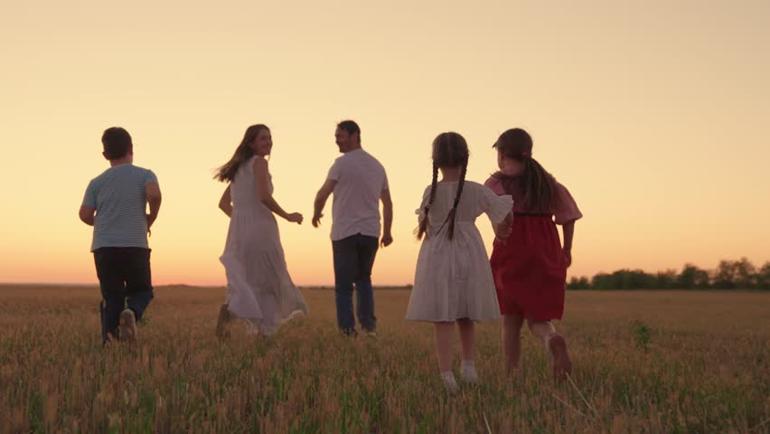 Family with children runs across field in evening at sunset. Big family, group of people in nature. Mom dad children. Son daughter mother father walk, run in outdoors. Family with children on vacation Royalty-Free Stock Footage #1106958057