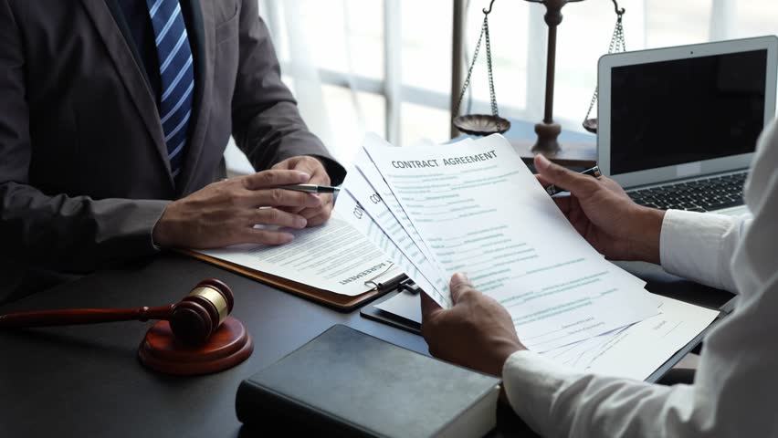 Attorneys or lawyers who are reading the statute of limitations Consultation between male lawyers and business clients, tax and legal and legal services firms. Royalty-Free Stock Footage #1106959273