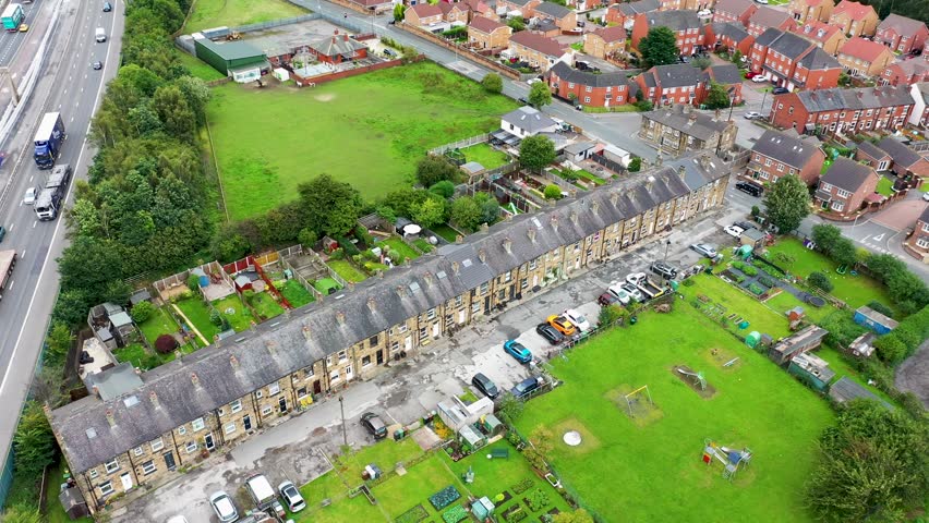 Aerial footage of the village of East Ardsley in the City of Leeds metropolitan borough, in West Yorkshire, England showing typical British housing estate and rows of terrace houses in the summer