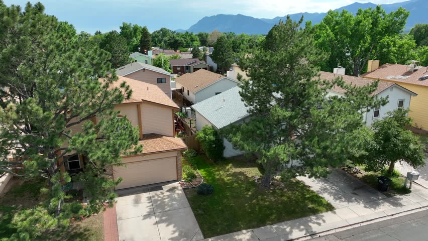 Houses in Colorado neighborhood. Aerial rising shot revealing large housing development with view of Rocky Mountains in distance.