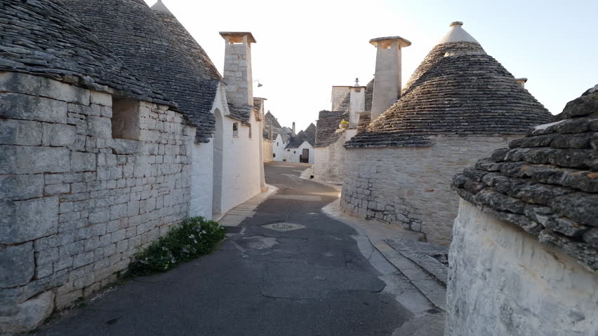 Alberobello Italy - traditional trulli houses with conical stone roofs. Famous landmark, travel destination and tourist attraction near Bari in Puglia, Europe. Street with ancient architecture. Royalty-Free Stock Footage #1106976045