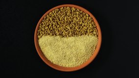 Fenugreek powder and Fenugreek seeds in the plate, top view. 4K video, Rotating clockwise. Healthy seeds of plant Trigonella foenum-graecum. Used in culinary and alternative medicine.