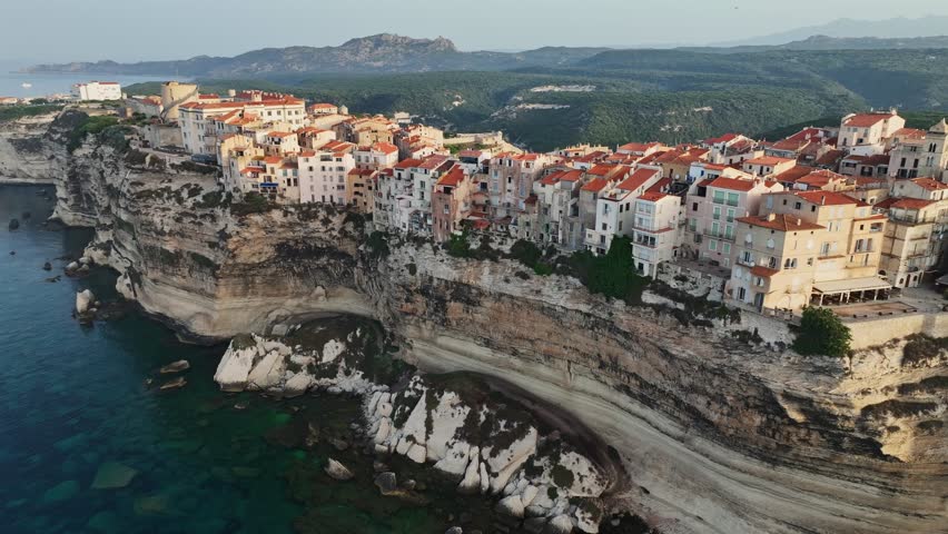Houses on cliff in the rays of rising sun in Bonifacio old town, Corsica, France. Aerial morning view of Bonifacio, Corsica island. Mediterranean sea Royalty-Free Stock Footage #1106988241