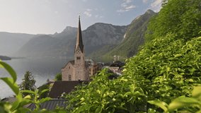 Gimbal shot of Hallstatt village on Hallstatter lake in Austrian Alps. Camera moves between green leaves in Hallstatt village at sunrise, Austria. Morning 4K shot - Powered by Shutterstock - Get 15% off with code: PIKWIZARD15