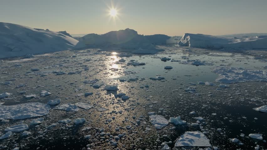 Aerial view of setting sun over icebergs. Ilulissat, Greenland. Glaciers melting, global warming, arctic nature landscape