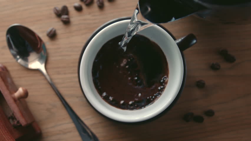 Soft focus slow motion on top view a hot water pouring into a cup from a teapot for making instant coffee. Hot water is pouring from the kettle. 4K