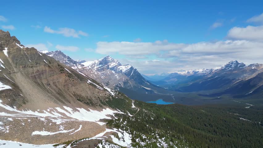 Cinematic aerial drone shot of the canadian rocky mountains looking at Peyto Lake with some snow