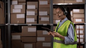 Female worker wearing headset walking in logistics distribution warehouse calling and using digital tablet - Powered by Shutterstock - Get 15% off with code: PIKWIZARD15