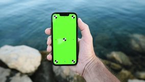 Smartphone mockup in male hand by the sea, selective focus - Powered by Shutterstock - Get 15% off with code: PIKWIZARD15