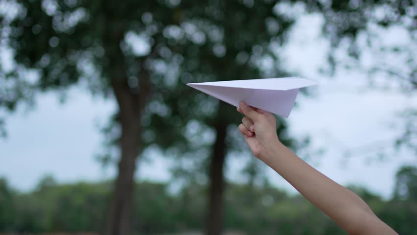 A little girl is happy and playing with white paper plane.