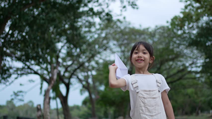 A little girl is happy and playing with white paper plane.