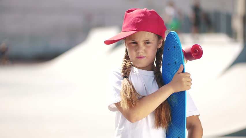 Portrait child girl skateboarder on the playground. Girl skateboarder on the background of the urban landscape area. happy family child dream concept. Skateboarder girl child lifestyle outdoor