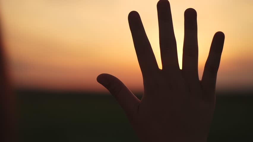 closeup hand at sunset.religion faith in god concept. the hand is turned to sun. the sun's rays fall on the hand. the girl's hand is turned to God in prayer. religion in every moment of life lifestyle Royalty-Free Stock Footage #1107007873