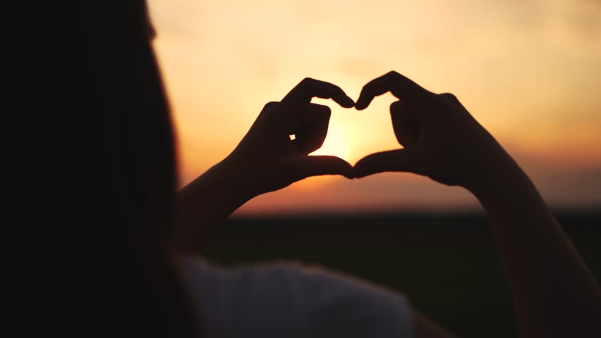 hands make a heart at sunset.happy family kid dream concept. hands in the foreground fold the figure from the fingers. a heart of fingers folded in a field at sunset lifestyle Royalty-Free Stock Footage #1107007879