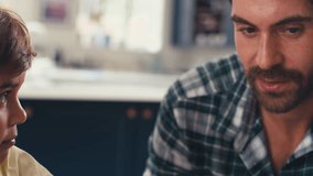 Close up of father in kitchen at home with son sitting at table helping with homework - shot in slow motion - Powered by Shutterstock - Get 15% off with code: PIKWIZARD15