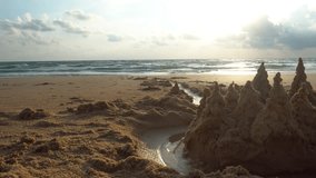 Sand castle on the beach with a view of the sea and clouds. Small raindrops fall on the sand. The sun is shining brightly. The rays are reflected from the water. Sharp castle towers. Thailand, Phuket - Powered by Shutterstock - Get 15% off with code: PIKWIZARD15