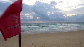 A red flag is a ban on swimming in this place. Yellow sand of the beach, sunset with big blue clouds. Waves in the sea. The guy is engaged in kitesurfing. Translation: Don't swim in this area - Powered by Shutterstock - Get 15% off with code: PIKWIZARD15