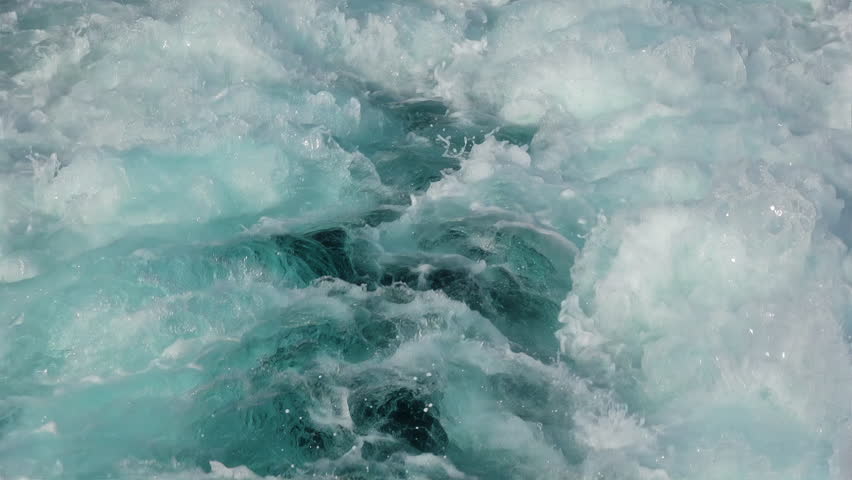 Slow-motion close-up of powerful, clear turquoise waves foaming and splashing. The water's surface exhibits a stunning abstract texture, created by the rapid movement of a boat. Seamless loop. | Shutterstock HD Video #1107009801