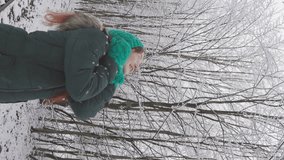 The magic of Christmas goes along with a woman enjoying winter walks in a snowy forest. Vertical video of a man in a fabulous snow-covered forest in winter. The picturesque nature and beauty of winter