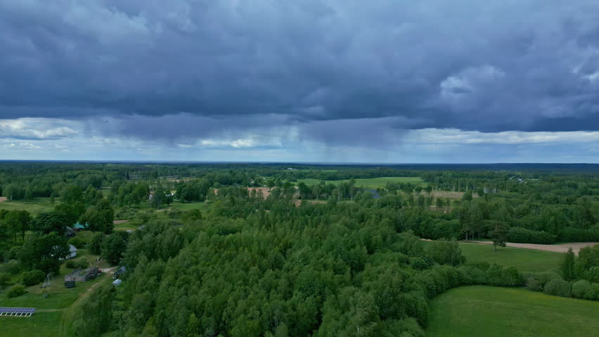 Aerial drone view of a green landscape and rain falling in the distance
