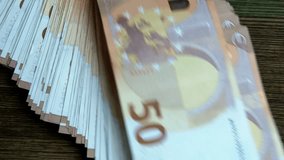 closeup paper 50 euro banknotes of eu slowly fall on old wooden table, slide along it, concept of cash, payments, savings, banking, return money debt, car, win in casino, get passive income - Powered by Shutterstock - Get 15% off with code: PIKWIZARD15