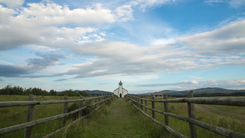 4k time lapse wide shot of a small white country church with ranch style fence, Alberta, Canada