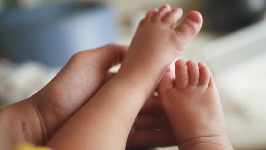 baby feet close up. dad holds a baby daughter legs in hands close-up indoors. happy family kid dream concept. feet toes close-up of newborn lifestyle in the hands of a parent