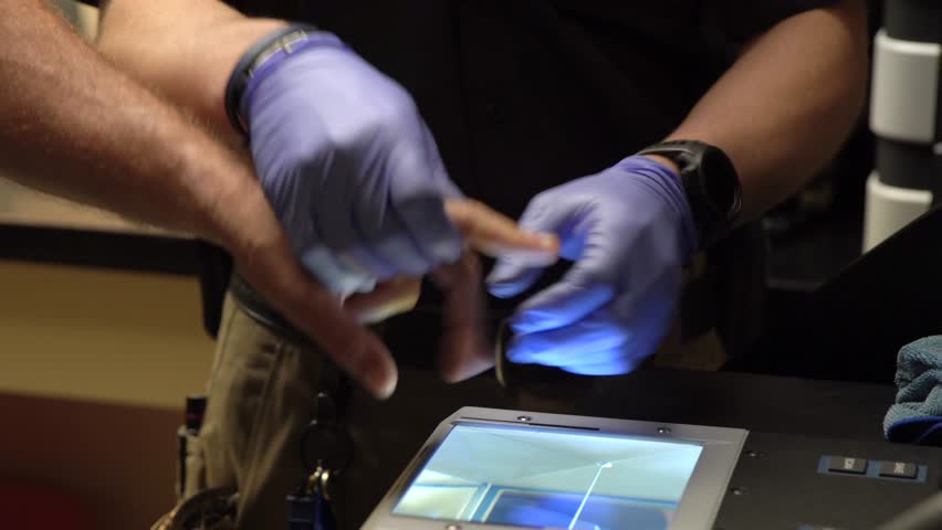 A security man with gloves taking fingerprints of a person on a scanning device Royalty-Free Stock Footage #1107034717