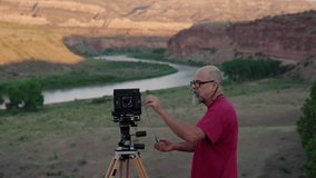 A shaky footage of an old wildlife photographer getting ready and turning on his devices