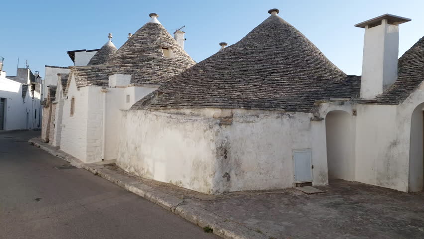 Alberobello Italy - traditional trulli houses with conical stone roofs. Famous landmark, travel destination and tourist attraction near Bari in Puglia, Europe. Street with ancient architecture. | Shutterstock HD Video #1107037155