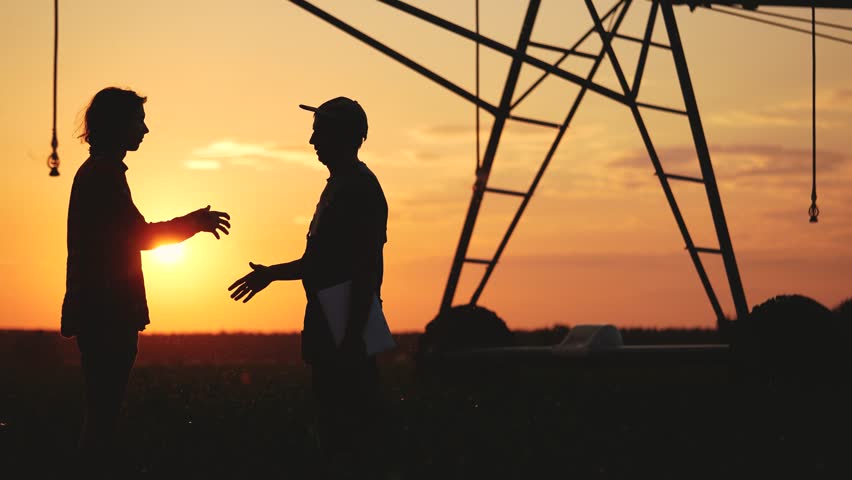 handshake agriculture. silhouette two farmers sign a contract shake hands on the background of an irrigation machine in cornfield. business handshake agriculture lifestyle irrigation concept Royalty-Free Stock Footage #1107037225