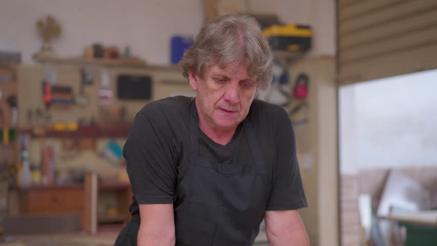 Senior Business Owner in Carpentry Workshop Feeling Stress About Economic Downturn, Worried Expression While Wearing Apron Royalty-Free Stock Footage #1107039481