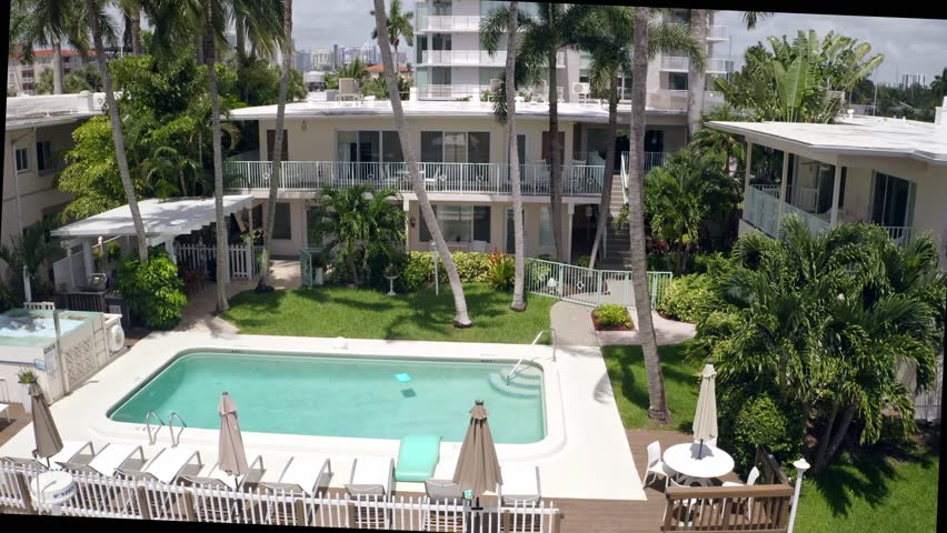 Aerial drone  Footage in Miami, Florida, USA, commercial area, luxury houses, buildings and mansions, abundant tropical vegetation around, blue sky and Ocean.