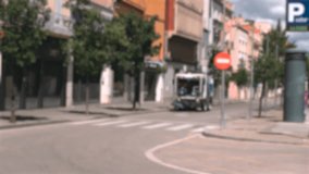 Background, blurry video. A special vehicle for garbage collection sweeps the street of the city with brushes.