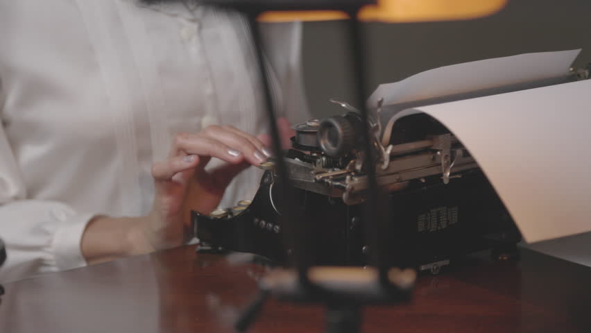 A scene that tracks right of a woman who is working in her office typing on a manual typewriter common in the 1930s.