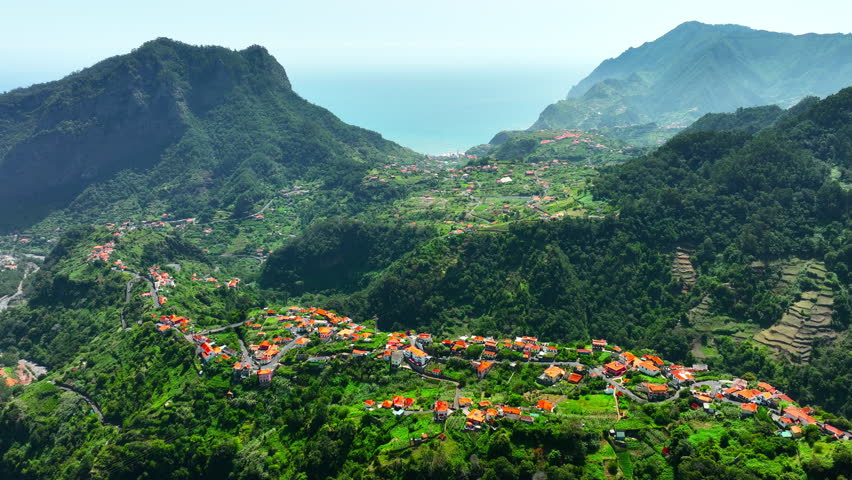 Aerial above small town, Village at mountain during summer golden hour at shore. Madeira, Portugal.